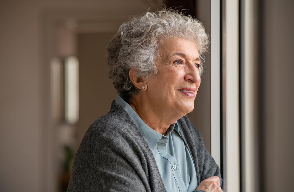 Smiling elderly woman looking out a window