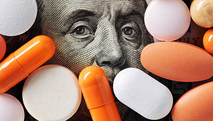 Portrait of Benjamin Franklin on a U.S. hundred-dollar bill, partially overlaid and surrounded by scattered pills of various shapes and colors.